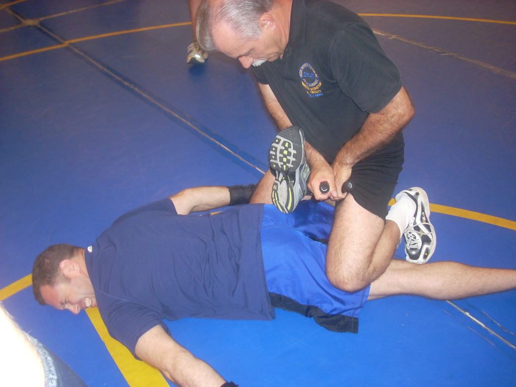 Man in blue being restrained by the ankle.