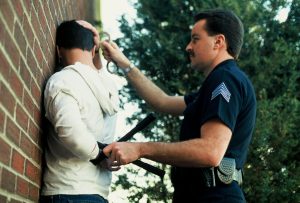 Officer cuffing subject on wall.